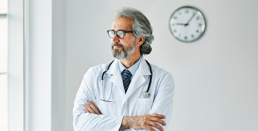 Medical professional man standing by a clock