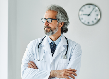 Medical professional man standing by a clock